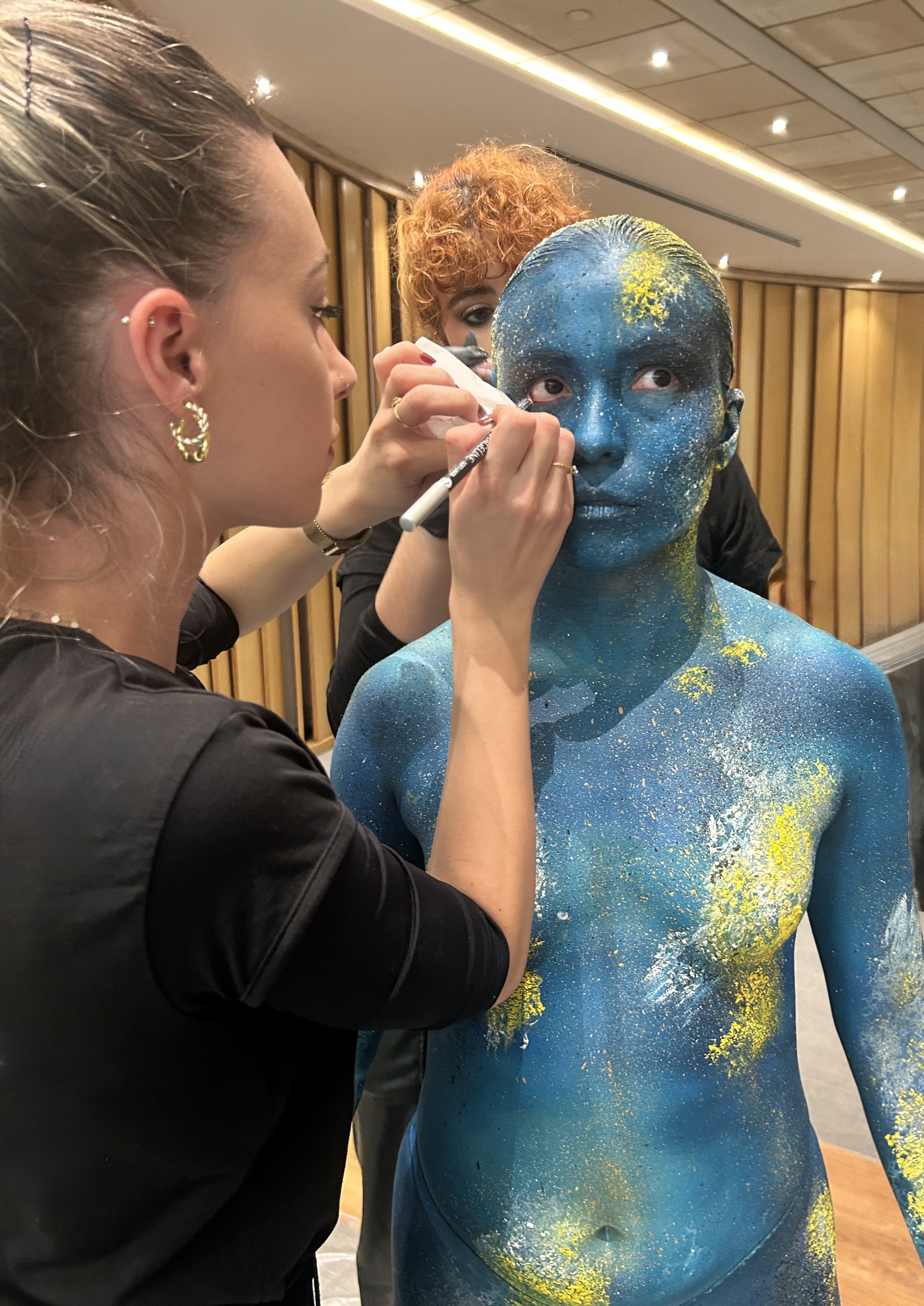 Laura Gil Sánchez applying blue body paint backstage